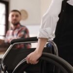 Zdjęcie osoby na wózku inwalidzkim, składającej wniosek o dotację w urzędzie.