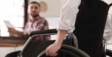 Zdjęcie osoby na wózku inwalidzkim, składającej wniosek o dotację w urzędzie.